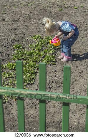 Girl watering plants with her watering can View Large Photo Image Stock Photography - Girl watering plants with her watering can. Fotosearch