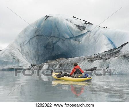Kayaker paddling beside ice cave at Valdez Glacier, Alaska, USA View Large Photo Image Stock Image - Kayaker paddling beside ice cave at Valdez Glacier, Alaska, USA. Fotosearch