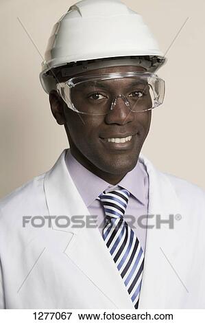 Laboratory worker wearing hard hat, protective goggles and lab coat View Large Photo Image Stock Photo - Laboratory worker wearing hard hat, protective goggles and lab coat. Fotosearch
