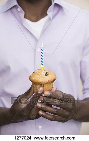 Man holding muffin with single candle on top View Large Photo Image Picture - Man holding muffin with single candle on top. Fotosearch