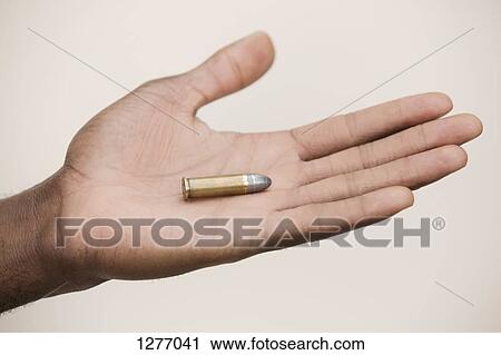 Man holding out a single bullet View Large Photo Image Stock Image - Man holding out a single bullet. Fotosearch