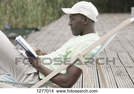 Man reading and relaxing on deck chair View Large Photo Image Picture - Man reading and relaxing on deck chair. Fotosearch