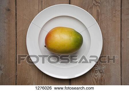 Mango on plate laying on wooden table View Large Photo Image Stock Photograph - Mango on plate laying on wooden table. Fotosearch
