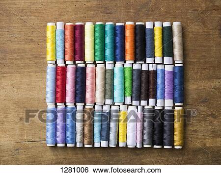 Rows of various colored spools of thread on a wooden table View Large Photo Image Stock Photograph - Rows of various colored spools of thread on a wooden table. Fotosearch