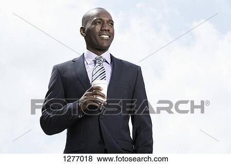 Stock Photo - Smiling businessman holding disposable coffee cup. Fotosearch