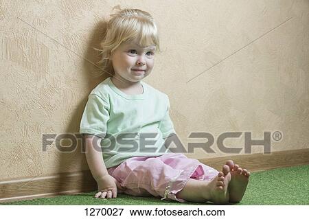 Smiling girl sitting against wall View Large Photo Image Stock Photo - Smiling girl sitting against wall. Fotosearch
