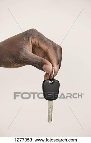 Studio shot of man holding car key View Large Photo Image Stock Image - Studio shot of man holding car key. Fotosearch