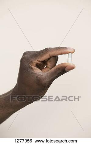 Studio shot of man holding single capsule View Large Photo Image Stock Photograph - Studio shot of man holding single capsule. Fotosearch