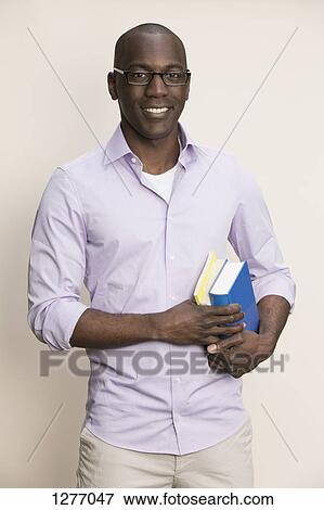 Studious man holding books View Large Photo Image Stock Photo - Studious man holding books. Fotosearch