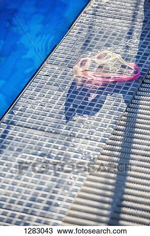 Sunlight shining on a pair of swimming goggles on the edge of a swimming pool View Large Photo Image Stock Image - Sunlight shining on a pair of swimming goggles on the edge of a swimming pool. Fotosearch