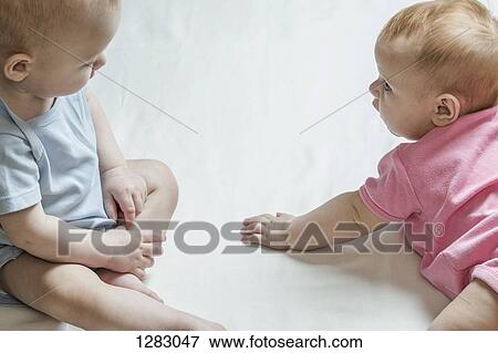 Stock Photo - Two babies looking at each other curiously. Fotosearch