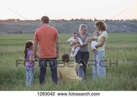Two families relaxing in a field in a rural setting View Large Photo Image Stock Image - Two families relaxing in a field in a rural setting. Fotosearch