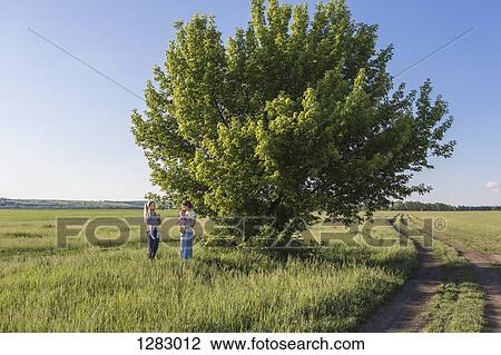 Stock Image - Two mothers holding their babies while standing in a field. Fotosearch