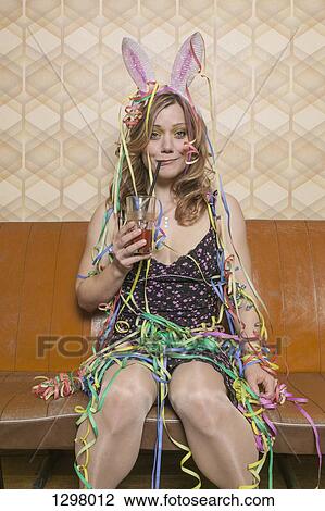 A tipsy woman drinking a cocktail and covered in streamers, portrait View Large Photo Image Stock Image - A tipsy woman drinking a cocktail and covered in streamers, portrait. Fotosearch