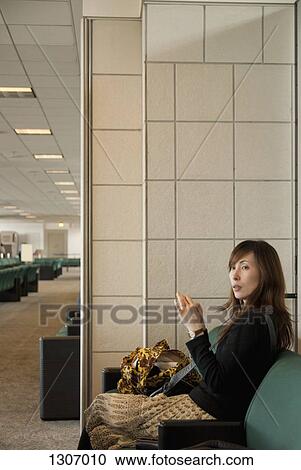 Stock Image - A woman sitting on a sofa in a waiting room. Fotosearch