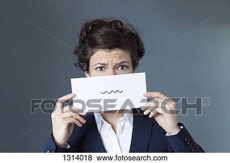 A worried looking woman holding paper with squiggle sign View Large Photo Image Stock Photo - A worried looking woman holding paper with squiggle sign. Fotosearch