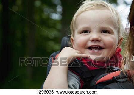 Baby boy riding in a carrier, piggyback with his mother, close-up View Large Photo Image Stock Photograph - Baby boy riding in a carrier, piggyback with his mother, close-up. Fotosearch