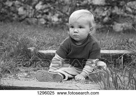Stock Photography - Baby boy sitting on ground, looking away. Fotosearch