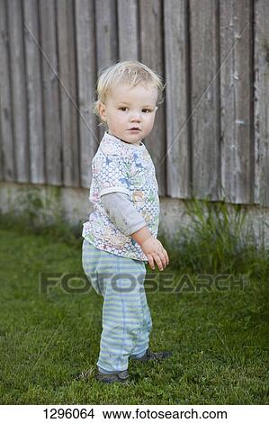 Picture - Baby boy standing on grass and looking away. Fotosearch