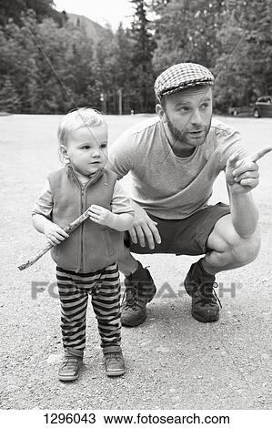 Stock Image - Baby boy with father looking away. Fotosearch