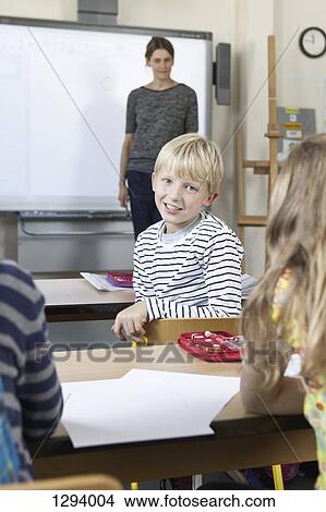 Boy sitting in classroom, smiling View Large Photo Image Picture - Boy sitting in classroom, smiling. Fotosearch