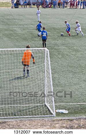 Stock Photo - Boys playing football at pitch. Fotosearch