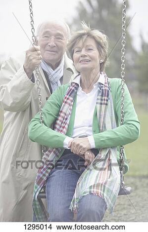Picture - Couple playing on park swing. Fotosearch