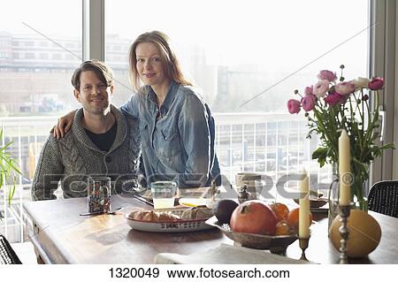 Stock Photo - Couple sitting at dining table with breakfast. Fotosearch