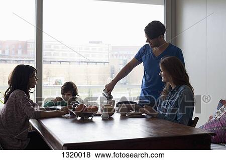 Stock Photo - Family having breakfast at dining table. Fotosearch