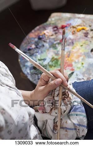 Stock Image - Female artist holding paintbrush, close-up. Fotosearch