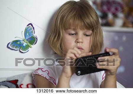 Stock Photograph - Girl playing on mobile phone, close-up. Fotosearch
