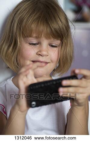 Girl playing on mobile phone, close-up View Large Photo Image Stock Photograph - Girl playing on mobile phone, close-up. Fotosearch
