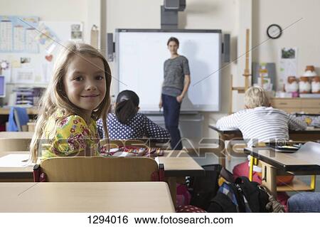Girl sitting in classroom, smiling View Large Photo Image Stock Photograph - Girl sitting in classroom, smiling. Fotosearch