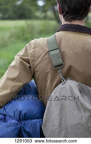 Stock Image - Man carrying sleeping bag and rucksack, close-up. Fotosearch