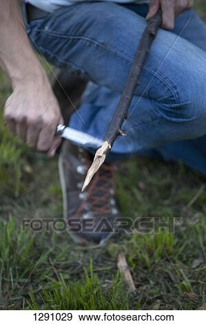 Stock Photo - Man cutting stick with knife, close-up. Fotosearch