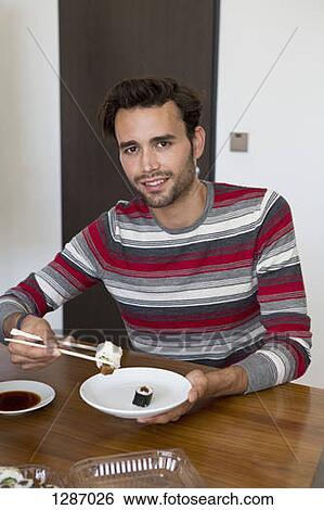 Man holding chopsticks and sushi, portrait View Large Photo Image Stock Photograph - Man holding chopsticks and sushi, portrait. Fotosearch