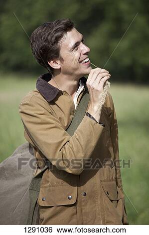 Man holding grass stalk, laughing View Large Photo Image Stock Photograph - Man holding grass stalk, laughing. Fotosearch