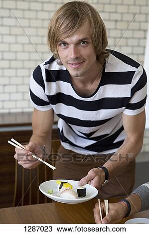 Man holding sushi and chopsticks, portrait View Large Photo Image Stock Image - Man holding sushi and chopsticks, portrait. Fotosearch