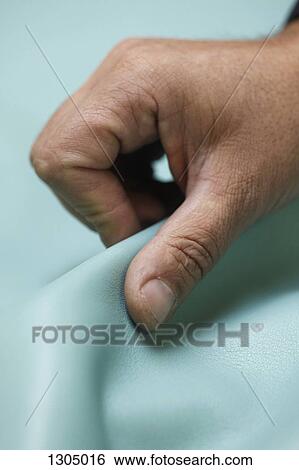Stock Photograph - Man holding turquoise textile, close-up. Fotosearch