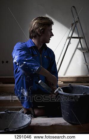 Man wearing workwear sitting with paint bucket View Large Photo Image Stock Photograph - Man wearing workwear sitting with paint bucket. Fotosearch