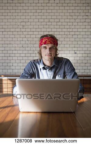 Man with laptop sitting at table, portrait View Large Photo Image Stock Photo - Man with laptop sitting at table, portrait. Fotosearch