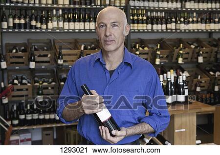 Mature man holding wine bottle in wine shop, portrait View Large Photo Image Stock Image - Mature man holding wine bottle in wine shop, portrait. Fotosearch