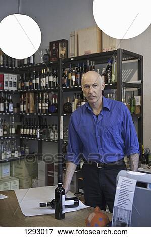 Mature man standing in wine shop, portrait View Large Photo Image Stock Photo - Mature man standing in wine shop, portrait. Fotosearch