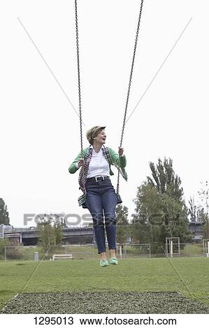 Stock Image - Mature woman swinging in park. Fotosearch
