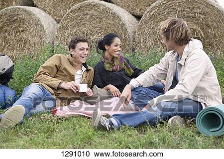 Men and woman resting in field and having drink View Large Photo Image Stock Image - Men and woman resting in field and having drink. Fotosearch