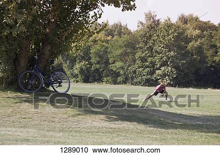 Stock Image - Mid adult man exercising in park. Fotosearch