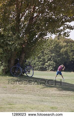 Mid adult man exercising in park View Large Photo Image Stock Image - Mid adult man exercising in park. Fotosearch
