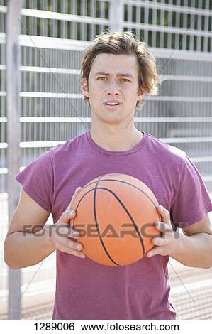 Stock Photograph - Mid adult man holding basketball, portrait. Fotosearch