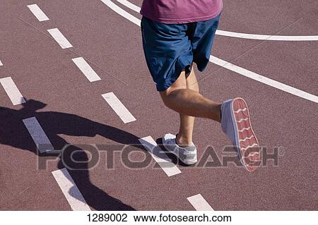 Stock Image - Mid adult man jogging, low section. Fotosearch