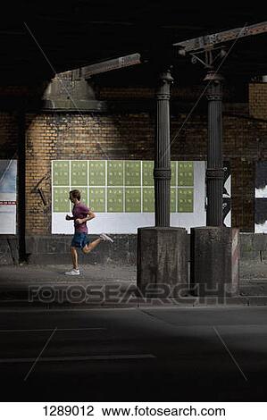 Mid adult man jogging on footpath View Large Photo Image Stock Image - Mid adult man jogging on footpath. Fotosearch